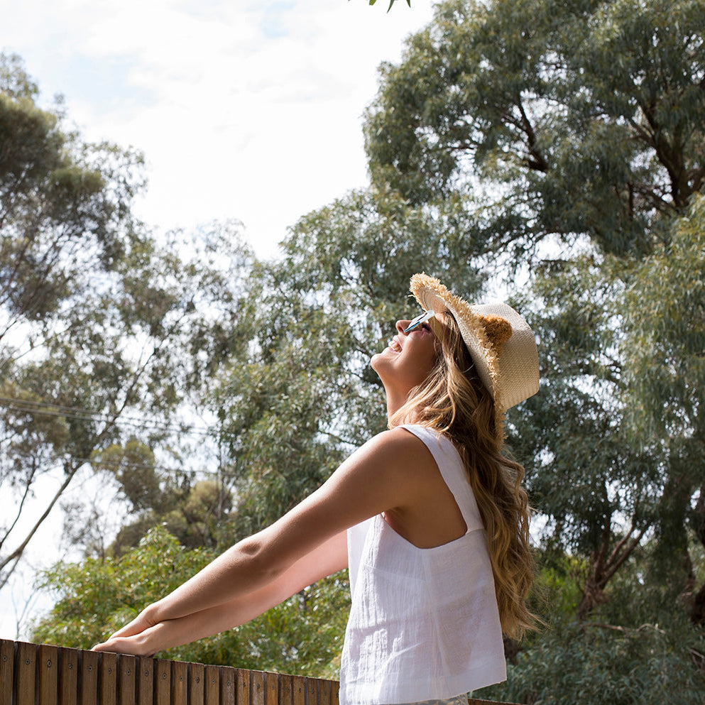 Woman wearing Happy on the Fringe natural handwoven sun hat outdoors