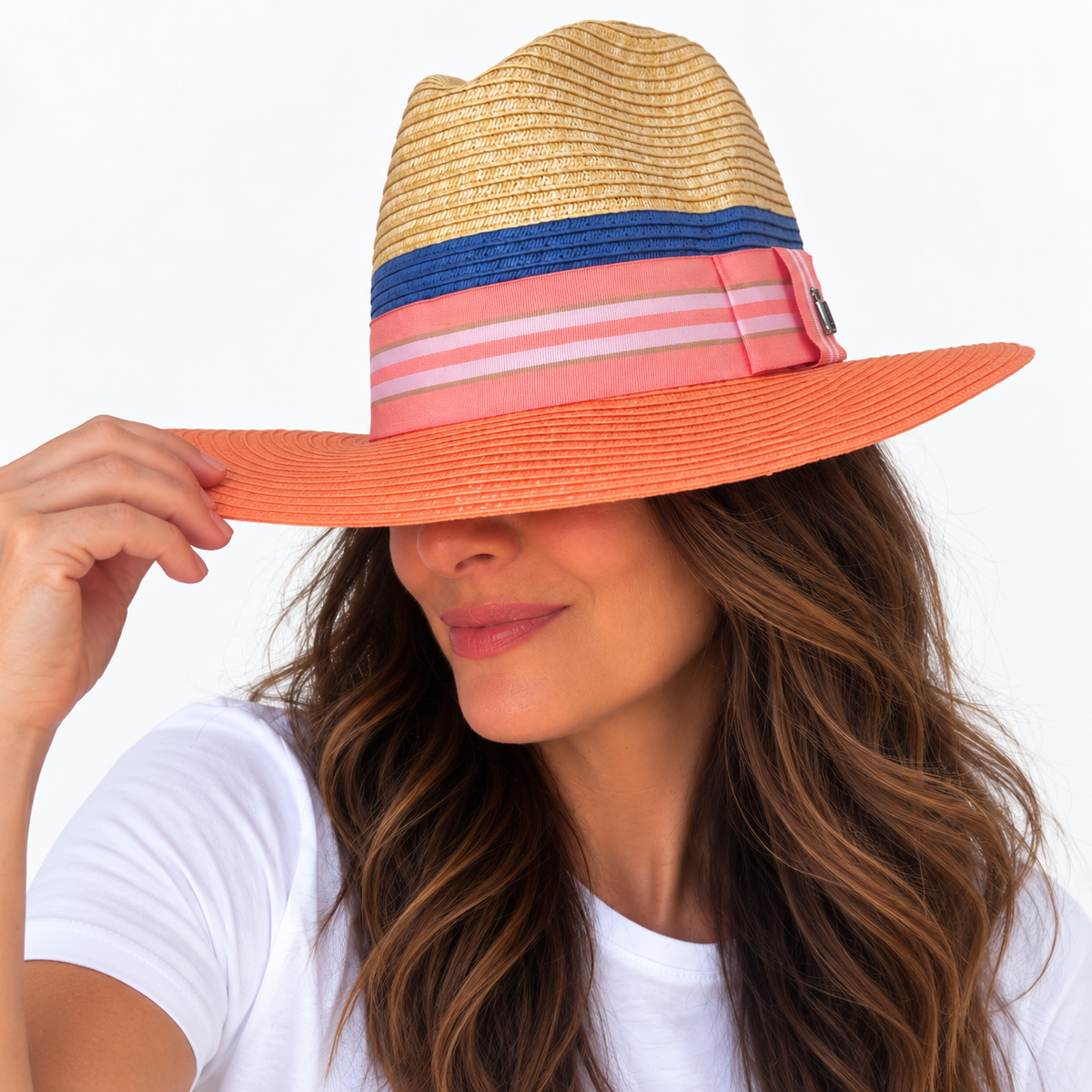 Miami Peach natural and peach paper hat with striped grosgrain ribbon worn by woman holding brim